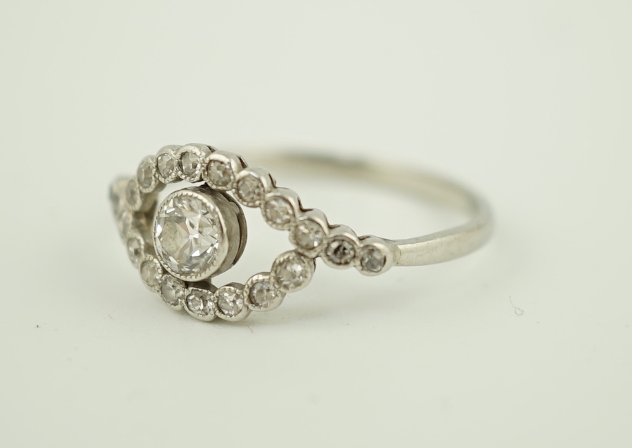 A white metal and single stone elliptical shaped ring, with diamond set border and shoulders, size M, gross weight 2.1 grams.